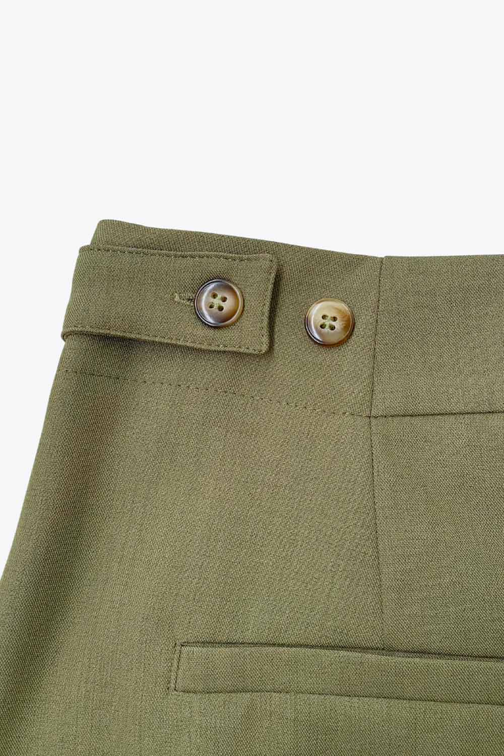 Pantalón de fit wide leg, cintura media con pretina, trabillas ajustables laterales, pinzas frontales, bolsillos delanteros y vivos decorativos posteriores. Cierre frontal con broche y cremallera ocultos.