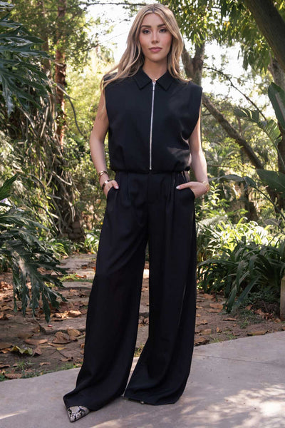 Pantalón de fit wide leg, cintura media con pretina, trabillas ajustables laterales, pinzas frontales, bolsillos delanteros y vivos decorativos posteriores. Cierre frontal con broche y cremallera ocultos.