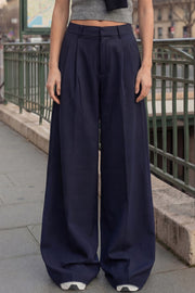 Pantalón de fit wide leg, cintura media con pretina, trabillas ajustables laterales, pinzas frontales, bolsillos delanteros y vivos decorativos posteriores. Cierre frontal con broche y cremallera ocultos.