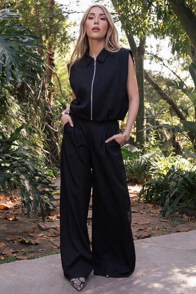 Pantalón de fit wide leg, cintura media con pretina, trabillas ajustables laterales, pinzas frontales, bolsillos delanteros y vivos decorativos posteriores. Cierre frontal con broche y cremallera ocultos.