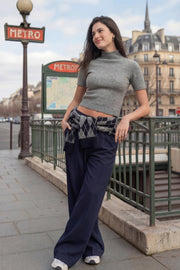 Pantalón de fit wide leg, cintura media con pretina, trabillas ajustables laterales, pinzas frontales, bolsillos delanteros y vivos decorativos posteriores. Cierre frontal con broche y cremallera ocultos.