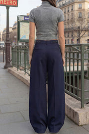 Pantalón de fit wide leg, cintura media con pretina, trabillas ajustables laterales, pinzas frontales, bolsillos delanteros y vivos decorativos posteriores. Cierre frontal con broche y cremallera ocultos.