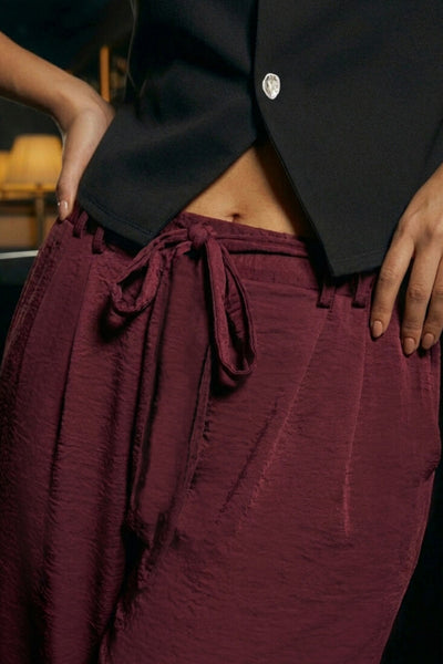 Pantalón de fit wide leg, cintura alta con pretina, trabillas y lazo amarrable en cintura, pinzas frontales y bolsillos delanteros. Cierre frontal con broche y cremallera oculta.