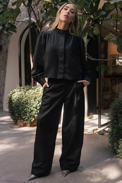 Pantalón de fit wide leg, cintura alta con pretina y trabillas, bolsillos decorativos delanteros, cierre frontal con botón y cremallera oculta.