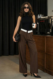 Pantalón de fit wide leg, pinzas frontales, cintura media, pretina con detalle de tailoring en contraste, bolsillos delanteros y vivos decorativos posteriores. Cierre frontal con broche y cremallera ocultos.