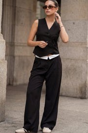 Pantalón de fit wide leg, pinzas frontales, cintura media, pretina con detalle de tailoring en contraste, bolsillos delanteros y vivos decorativos posteriores. Cierre frontal con broche y cremallera ocultos.