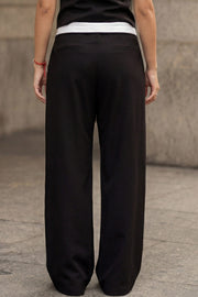 Pantalón de fit wide leg, pinzas frontales, cintura media, pretina con detalle de tailoring en contraste, bolsillos delanteros y vivos decorativos posteriores. Cierre frontal con broche y cremallera ocultos.