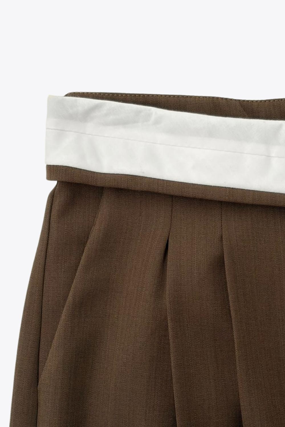 Pantalón de fit wide leg, pinzas frontales, cintura media, pretina con detalle de tailoring en contraste, bolsillos delanteros y vivos decorativos posteriores. Cierre frontal con broche y cremallera ocultos.