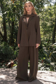 Pantalón de fit wide leg, cintura alta con pretina y trabillas, bolsillos delanteros y pinzas frontales. Cierre frontal con botón y cremallera oculta.