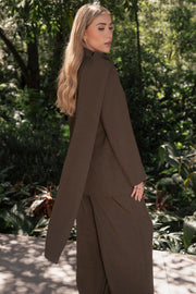 Pantalón de fit wide leg, cintura alta con pretina y trabillas, bolsillos delanteros y pinzas frontales. Cierre frontal con botón y cremallera oculta.