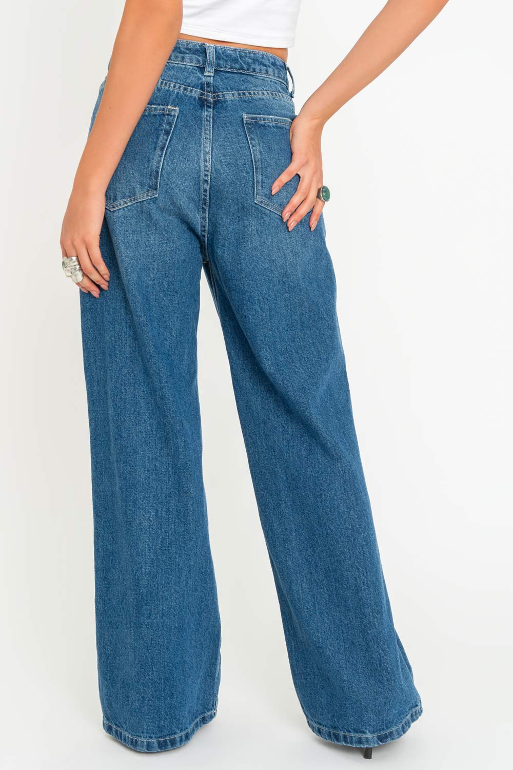 Pantalón wide leg de denim, cintura alta con pretina y trabillas, bolsillos delanteros y posteriores de parche. Cierre frontal con botón y cremallera oculta.