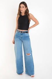 Pantalón wide leg de denim, cintura alta con pretina y trabillas, bolsillos delanteros y posteriores de parche. Cierre frontal con botón y cremallera oculta.