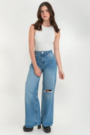 Pantalón wide leg de denim, cintura alta con pretina y trabillas, bolsillos delanteros y posteriores de parche. Cierre frontal con botón y cremallera oculta.