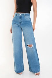 Pantalón wide leg de denim, cintura alta con pretina y trabillas, bolsillos delanteros y posteriores de parche. Cierre frontal con botón y cremallera oculta.