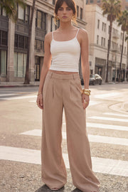 Pantalón de fit wide leg, cintura alta con pretina elástica posterior, trabillas, pinzas frontales y bolsillos delanteros.