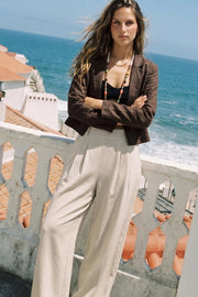 Pantalón de fit wide leg, cintura alta con pretina elástica posterior, trabillas, pinzas frontales y bolsillos delanteros.
