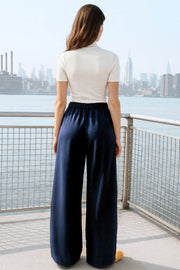 Pantalón de fit wide leg, cintura alta con pretina elástica posterior, trabillas, pinzas frontales y bolsillos delanteros.