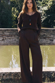 Pantalón de fit wide leg, cintura alta con pretina elástica posterior, trabillas, pinzas frontales y bolsillos delanteros.