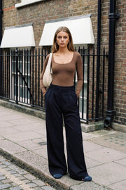 Pantalón de fit wide leg, pinzas frontales, cintura alta con pretina y trabillas, bolsillos delanteros, cierre frontal con broche y cremallera ocultos.