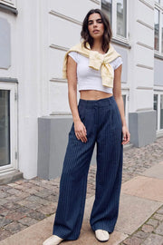 Pantalón wide leg de estampado rayas, cintura alta con pretina y trabillas, pinzas frontales, bolsillos delanteros y vivos decorativos posteriores. Cierre frontal con broche y cremallera ocultos. Detalle de trabillas ajustables con botón en costados.