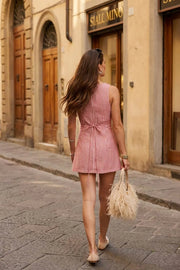 Playsuit de estampado rayas, fit ajustado, cuello barco, sin mangas, pinzas frontales, lazo amarrable posterior y cierre con cremallera oculta.