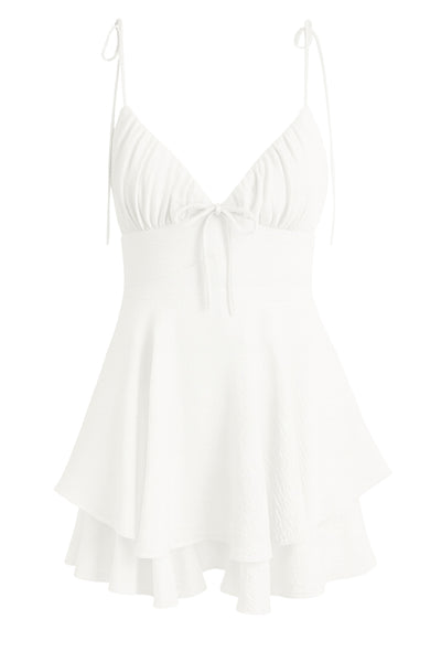 Playsuit de tirantes delgados con nudo amarrable, escote v con detalles plisados y lazo decorativo frontal, pretina cruzada frontal con lazo amarrable posterior y capas de olanes en bajo. Cierre posterior con cremallera visible en contraste.