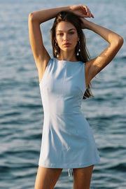 Playsuit de fit ajustado, cuello barco, sin mangas, pinzas frontales, lazo amarrable posterior y cierre con cremallera oculta.