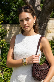 Playsuit de fit ajustado, cuello barco, sin mangas, pinzas frontales, lazo amarrable posterior y cierre con cremallera oculta. Detalle de textura en tejido.