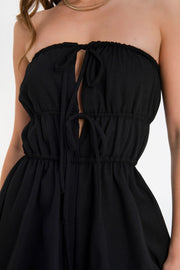 Playsuit strapless de escote recto con plisados y jareta frontal ajustable, cut outs con plisados y lazo amarrable, rib elástico en cintura y olanes en bajo.