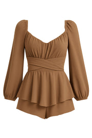 Playsuit de escote v redondeado con detalles plisados, manga larga abullonada con rib elástico en hombros y puños Detalle inferior de capas con olanes, pretina con cruce frontal y lazo amarrable posterior. Cierre con cremallera visible posterior.