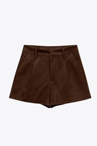 Short corto de gamuza, fit recto, cintura alta con pretina y trabillas, bolsillos delanteros y vivos decorativos posteriores. Detalle de pinzas frontales, cierre frontal con broche y cremallera ocultos.