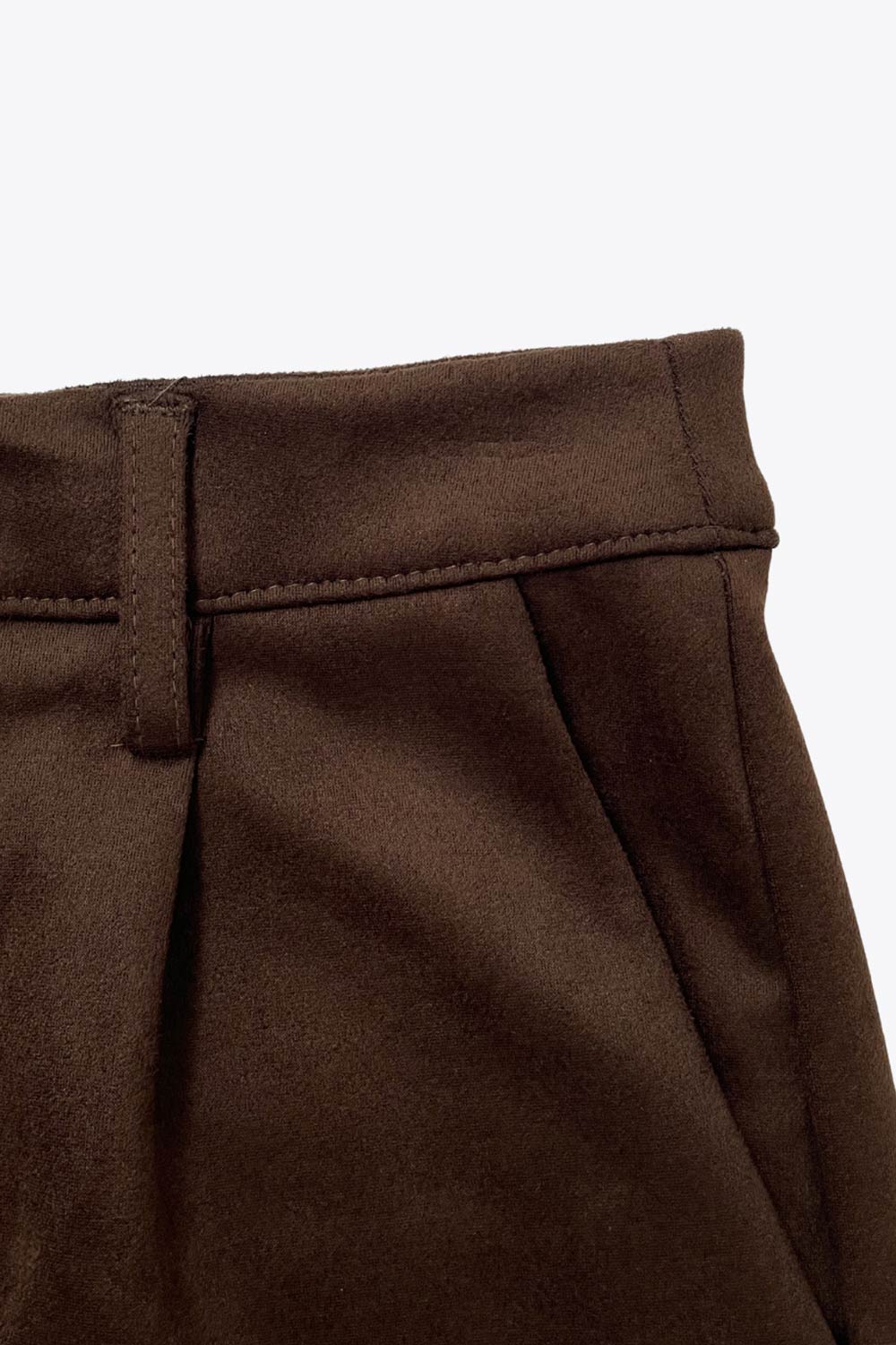 Short corto de gamuza, fit recto, cintura alta con pretina y trabillas, bolsillos delanteros y vivos decorativos posteriores. Detalle de pinzas frontales, cierre frontal con broche y cremallera ocultos.