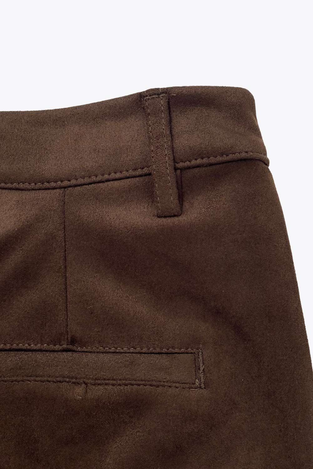 Short corto de gamuza, fit recto, cintura alta con pretina y trabillas, bolsillos delanteros y vivos decorativos posteriores. Detalle de pinzas frontales, cierre frontal con broche y cremallera ocultos.