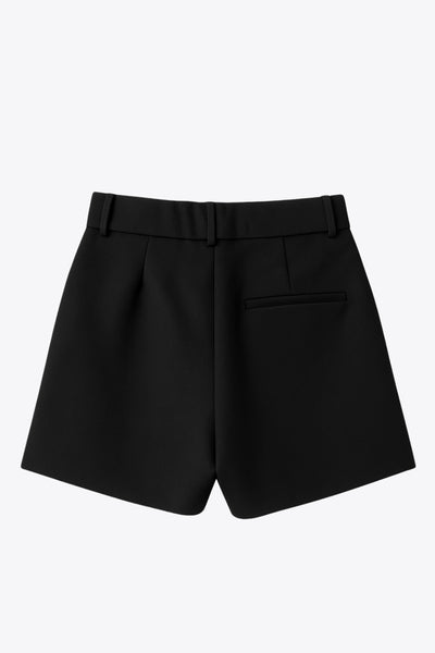 Short corto de cintura alta con pretina elástica posterior y trabillas, corte en a, pinzas frontales, bolsillos delanteros y vivo decorativo posterior. Cierre frontal con broche y cremallera oculta.