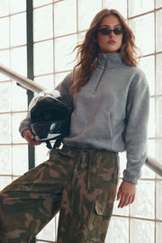 Sudadera de fit ligeramente oversized, manga larga con hombro caído, cuello sport, bolsillos delanteros y rib elástico en puños. Detalle de jaretas elásticas ajustables laterales en bajo. Cierre frontal con cremallera. Detalle de costura decorativo posterior.