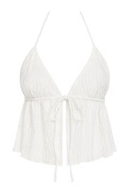 Top corto de escote v con lazo amarrable frontal, rib elástico en espalda, tirantes halter con lazo amarrable posterior y abertura frontal en bajo. Detalle de peplum olanes en bajo y textura en tejido.