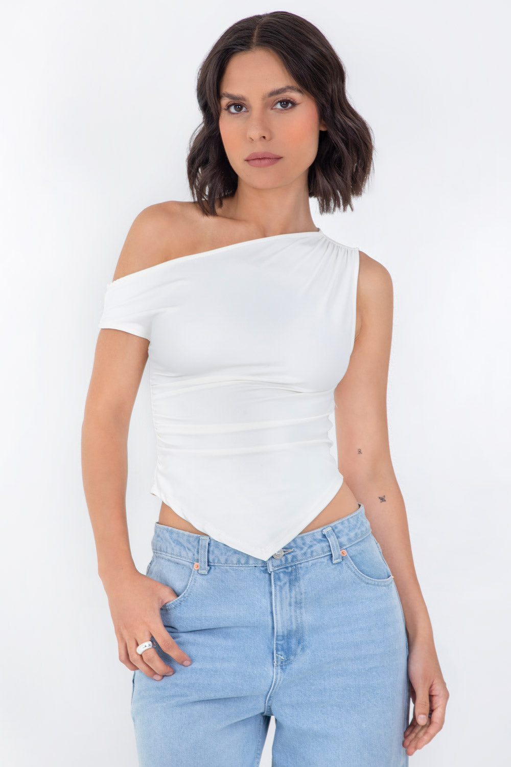 Top ajustado sin mangas, de cuello diagonal con hombro descubierto, plisados en hombros y bajo frontal asimétrico.