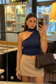 Top asimétrico de fit ajustado, detalles plisados laterales y en hombro, sin mangas, un hombro, escote diagonal y choker con plisados. Cierre posterior con botón y ojal.