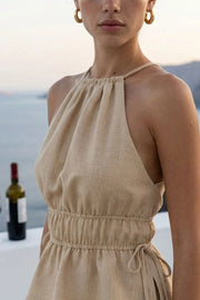 Top corto de cuello halter con plisados, tirantes delgados, detalle de rib con plisados y lazos laterales en costados, peplum con olanes en bajo y cierre posterior con botón y ojal.