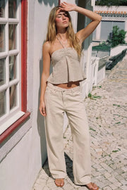 Top corto de estampado rayas, cuello halter con lazo amarrable posterior, escote corazón con jareta ajustable y plisados frontales. Detalle de peplum con olanes y fruncido en espalda.