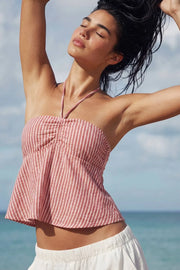 Top corto de estampado rayas, cuello halter con lazo amarrable posterior, escote corazón con jareta ajustable y plisados frontales. Detalle de peplum con olanes y fruncido en espalda.