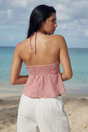 Top corto de estampado rayas, cuello halter con lazo amarrable posterior, escote corazón con jareta ajustable y plisados frontales. Detalle de peplum con olanes y fruncido en espalda.