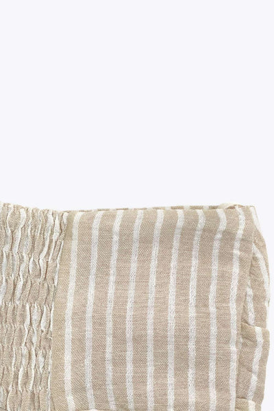 Top corto de estampado rayas, cuello halter con lazo amarrable posterior, escote corazón con jareta ajustable y plisados frontales. Detalle de peplum con olanes y fruncido en espalda.