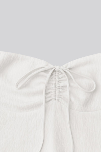 Top corto halter con lazo amarrable posterior, escote corazón con jareta ajustable y plisados frontales. Detalle de peplum con olanes y fruncido en espalda.