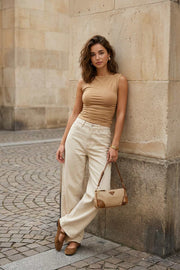 Top básico de fit ajustado, cuello barco, sin mangas, plisados en costados y hombros.