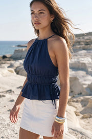 Top corto de cuello halter con tirantes delgados, fit ajustado, rib con plisados en cintura y cuello. Detalle de jaretas ajustables en cintura, cierre posterior con botón y ojal.