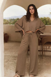 Blusa tipo capa de fit fluido, manga larga amplia, cuello v y bajo asimétrico. Detalle de textura en tejido.