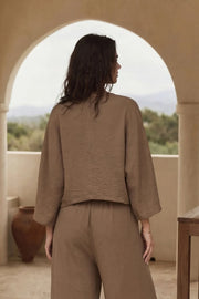 Blusa tipo capa de fit fluido, manga larga amplia, cuello v y bajo asimétrico. Detalle de textura en tejido.