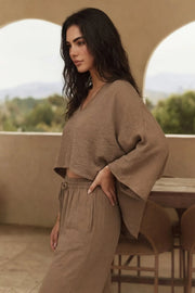 Blusa tipo capa de fit fluido, manga larga amplia, cuello v y bajo asimétrico. Detalle de textura en tejido.