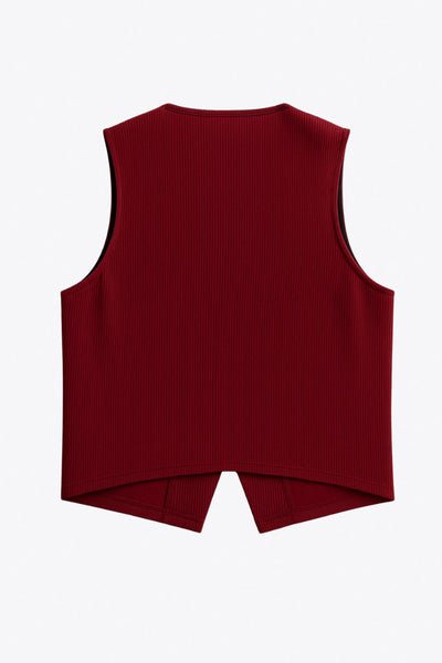 Chaleco canalé de punto, fit ajustado, escote redondo y cierre frontal con hilera de botones en contraste. Detalle de bajo v frontal.